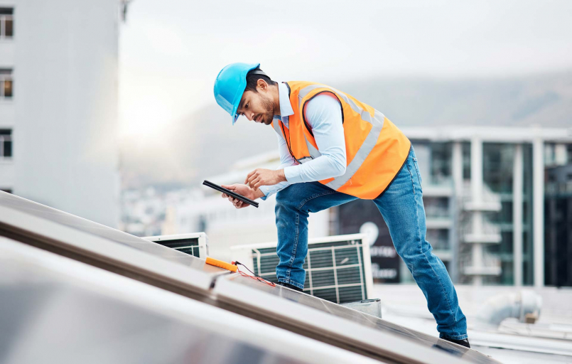 Worker on roof looking at solar panels